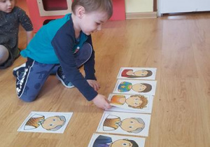 Chłopiec dopasowuje ilustrację emocji do ilustracji twarzy.